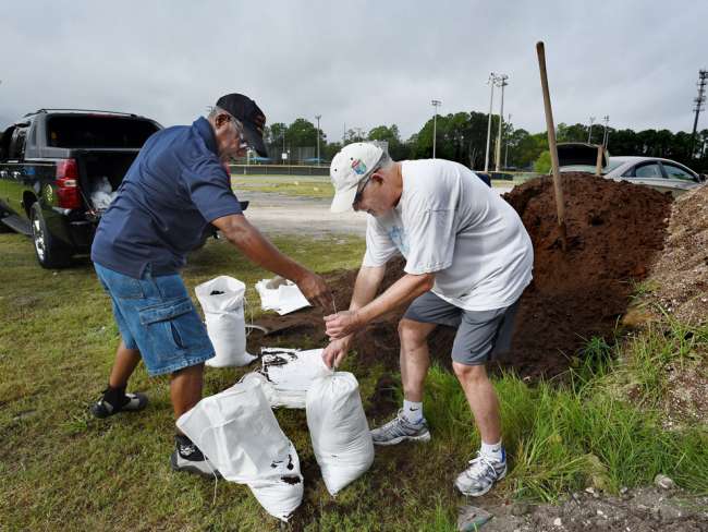 Darwin Driscoll assists Saint Johns resident Rob Selwitz with his sandbag filing technique as they prepare for the upcoming storm