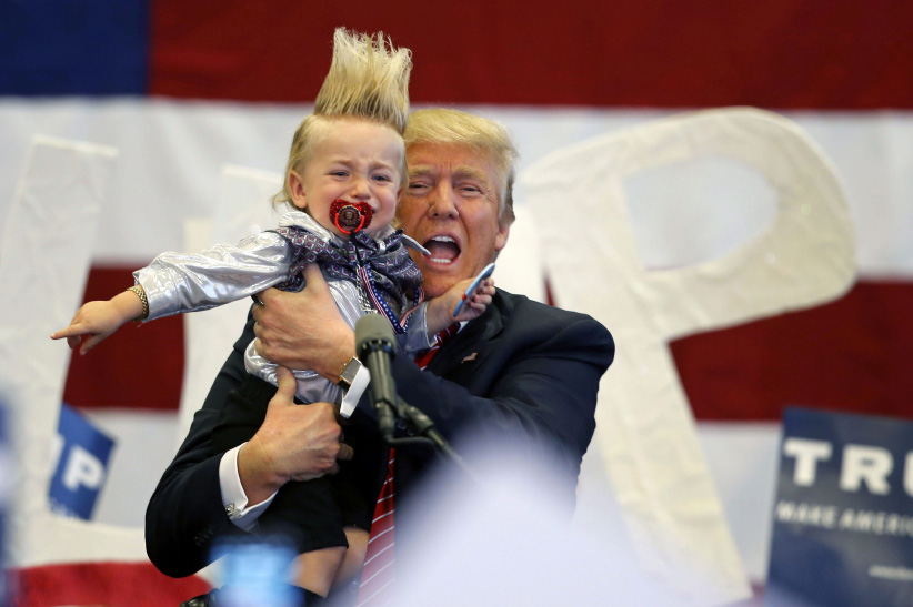 Republican presidential candidate Donald Trump holds up a child he pulled from the crowd as he arrives to speak at a campaign rally in New Orleans