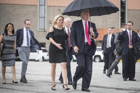 Republican presidential candidate Donald Trump walks in the rain with Florida Attorney General Pam Bondi as they arrive at a campaign rally in Tampa Fla. Wednesday Aug. 24 2016