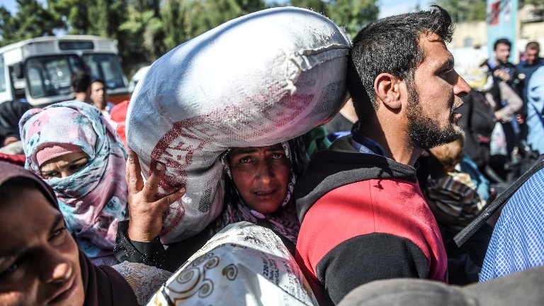 Syrian refugees walk on their way back to the Syrian city of Jarabulus