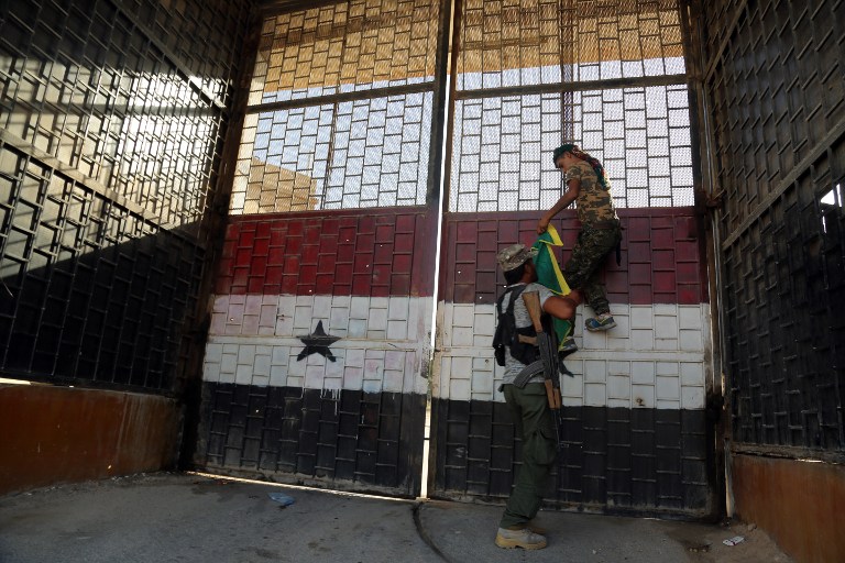 Kurdish fighters belonging to the People's Protection Units put a YPG flag on the door of the central prison in the northeastern Syrian city of Hasakeh