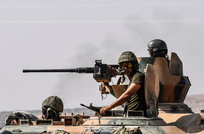 Turkish soldiers drive a tank towards Syria from the Turkish border city of Karkamis in the Gaziantep region