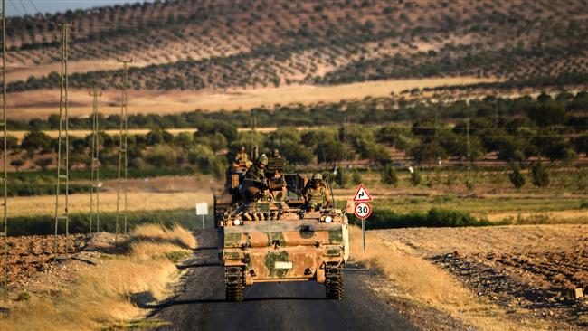 Turkish soldiers stand in an army tank driving back to Turkey from the Syrian town of Jarablus