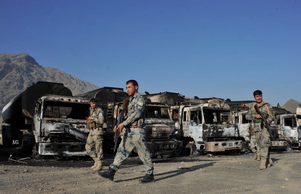 Afghan security personnel patrol near burned NATO supply oil tankers following an overnight attack by Taliban militants in the Torkham area near the Pakistan and Afghan border in the eastern Nangarhar province