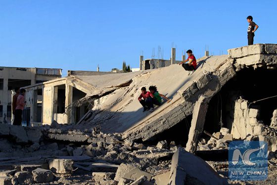 Syrian children slide down rubble of destroyed a building in the rebel-held city of Daraa in southwestern Syria