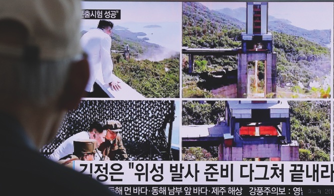 A man watches a TV news showing images that North Korea’s Rodong Sinmun newspaper reports of the ground test of a high-powered engine of a carrier rocket and North Korean leader Kim Jong Un at the country’s Sohae Space Center