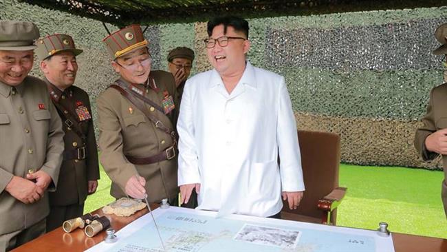 North Korean leader Kim Jong-un laughs during a fire drill of ballistic rockets by artillery units in this undated