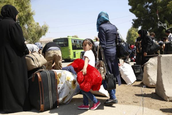 A girl clutches a teddy bear as she waits to board a bus leaving the Moadamiyeh suburb of Damascus Syria on Friday Sept. 2 2016