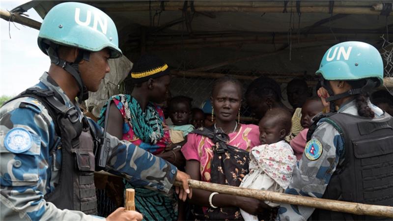 UN peacekeepers control South Sudanese women and children before the distribution of emergency food supplies in Juba