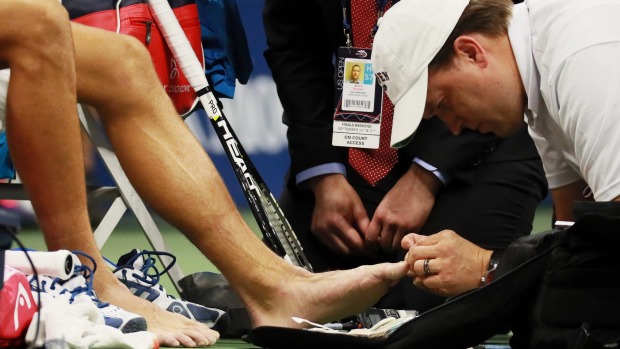 A trainer gives Novak Djokovic medical treatment on a toe during a controversial moment of the US Open men's singles final