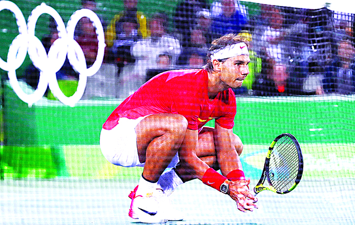 Rafael Nadal of Spain squats down low as partner Marc Lopez serves to Romania during the men’s doubles final round match at the 2016 Summer Olympics in Rio de Janeiro Brazil. Spain won the gold