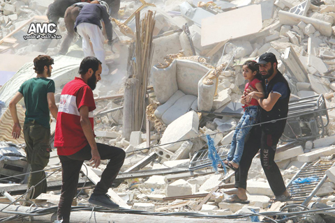 Syrian anti-government activist group Aleppo Media Center, shows a Syrian man carrying a girl away from the rubble of a destroyed building after barrel bombs were dropped on the Bab Al Nairab neighborhood. — AP