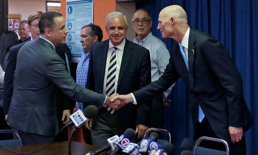 Florida Gov. Rick Scott shakes hands with Miami Beach Mayor Philip Levine as Miami Dade Mayor Carlos Gimenez looks on prior to a round table discussion about the Zika virus Aug. 22 at the De Hostos Senior Center in Miami. (Patrick Farrell  Miami He