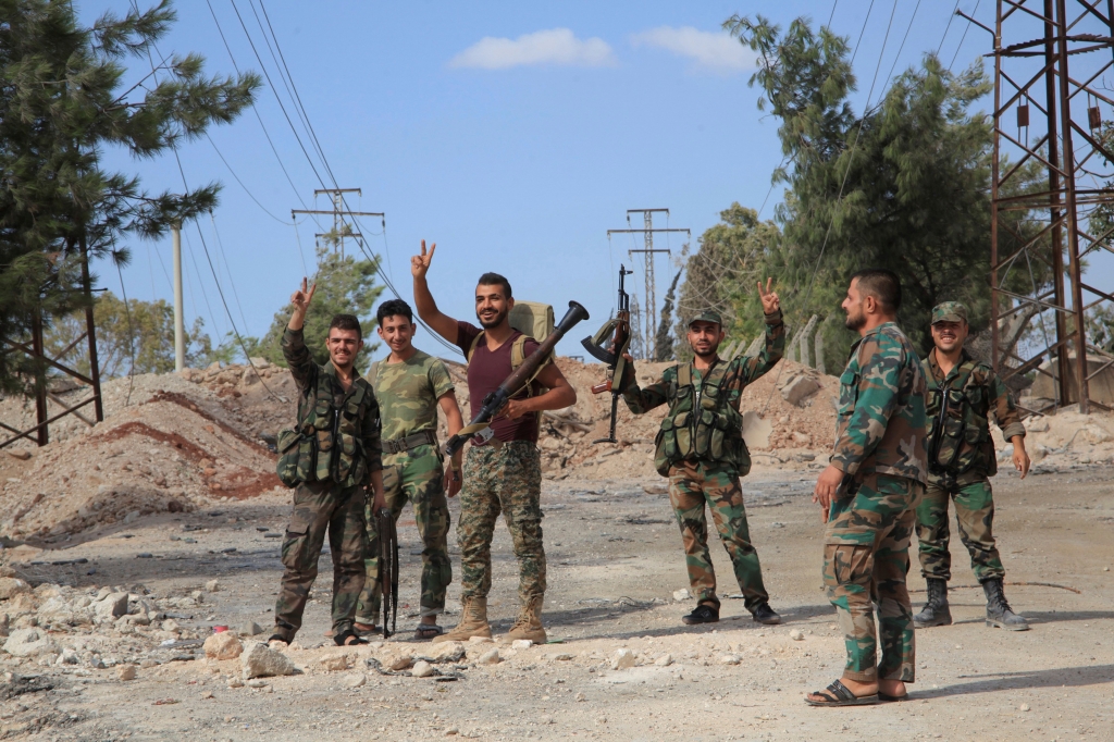 Forces loyal to Syria's President Bashar al Assad flash victory signs as they stand at a military complex after they recaptured areas in southwestern Aleppo on Sunday that rebels had seized last month Syria in this handout