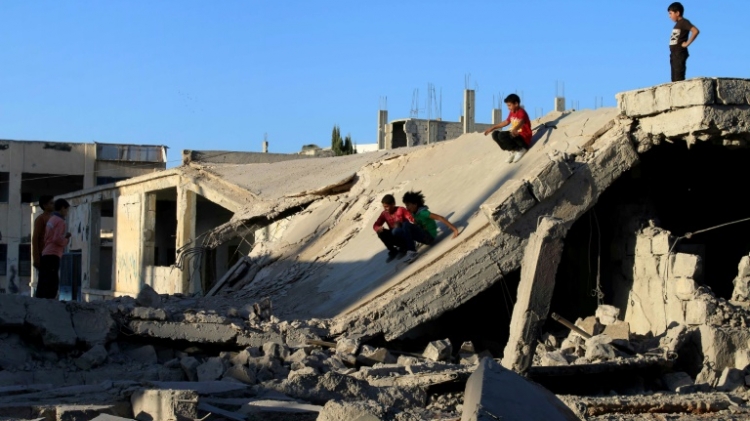 Syrian children slide down rubble of destroyed a building in the rebel-held city of Daraa