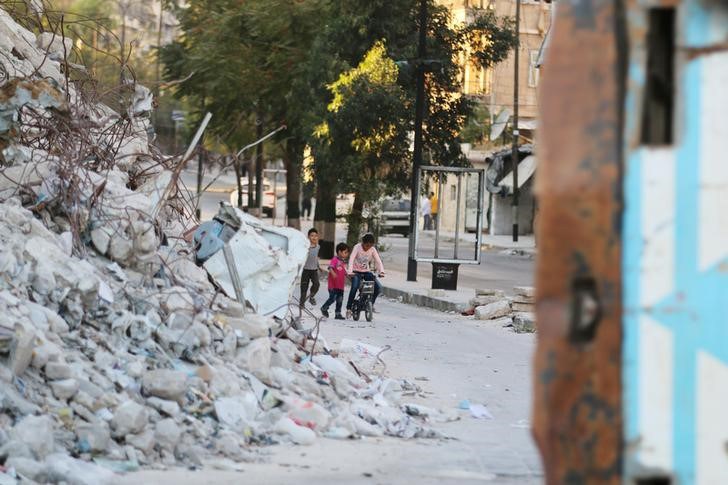 Children play with a bicycle near the rubble of damaged buildings in the rebel-held Bab al Hadid neighbourhood of Aleppo Syria