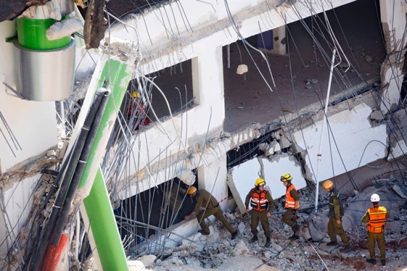 Israeli members of the Magen David Adom rescue service wait next to stretchers after an underground car park collapsed at a construction site