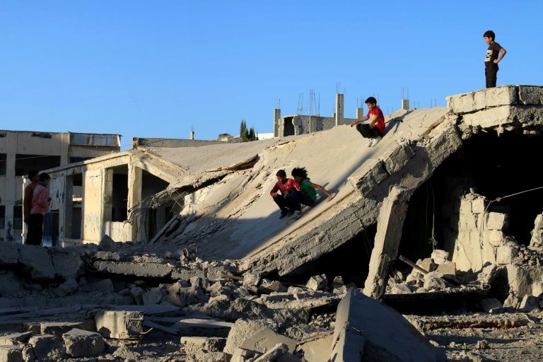 Syrian children slide down rubble of destroyed a building in the rebel-held city of Daraa