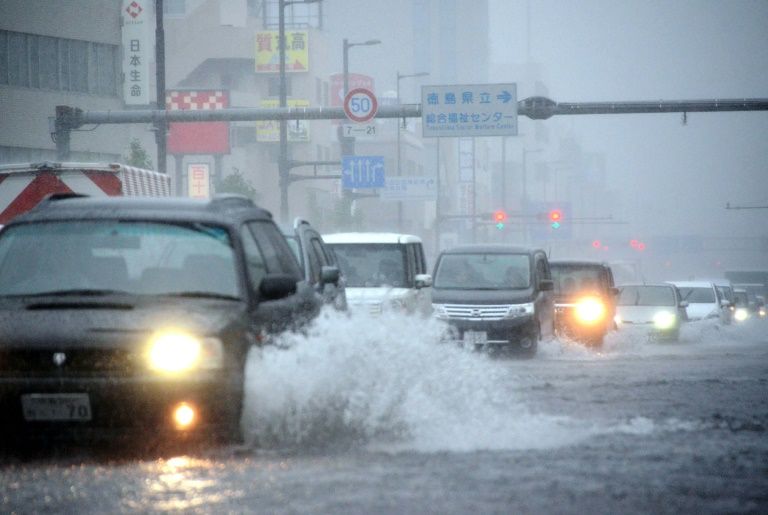 Vehicles drive through a flooded street in Tokushima Japan