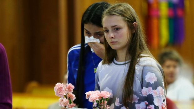 Rachel Marsh 15 right and Selena Orozco 15 left carry flowers as they attend a prayer service on Saturday for the