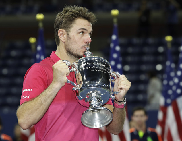 Stan Wawrinka of Switzerland kisses the championship trophy after beating Novak Djokovic of Serbia to win the men's singles final of the U.S. Open tennis