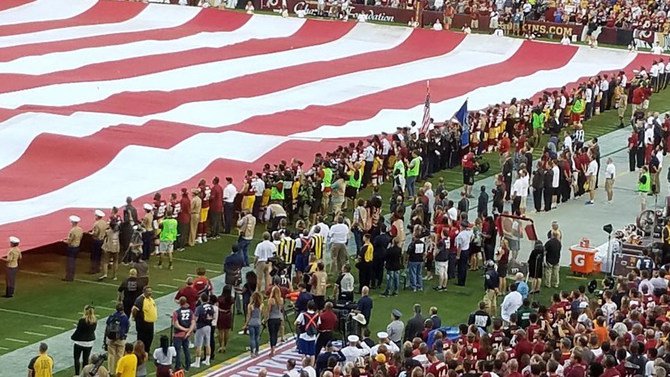 The Redskins hold the American flag for the national anthem