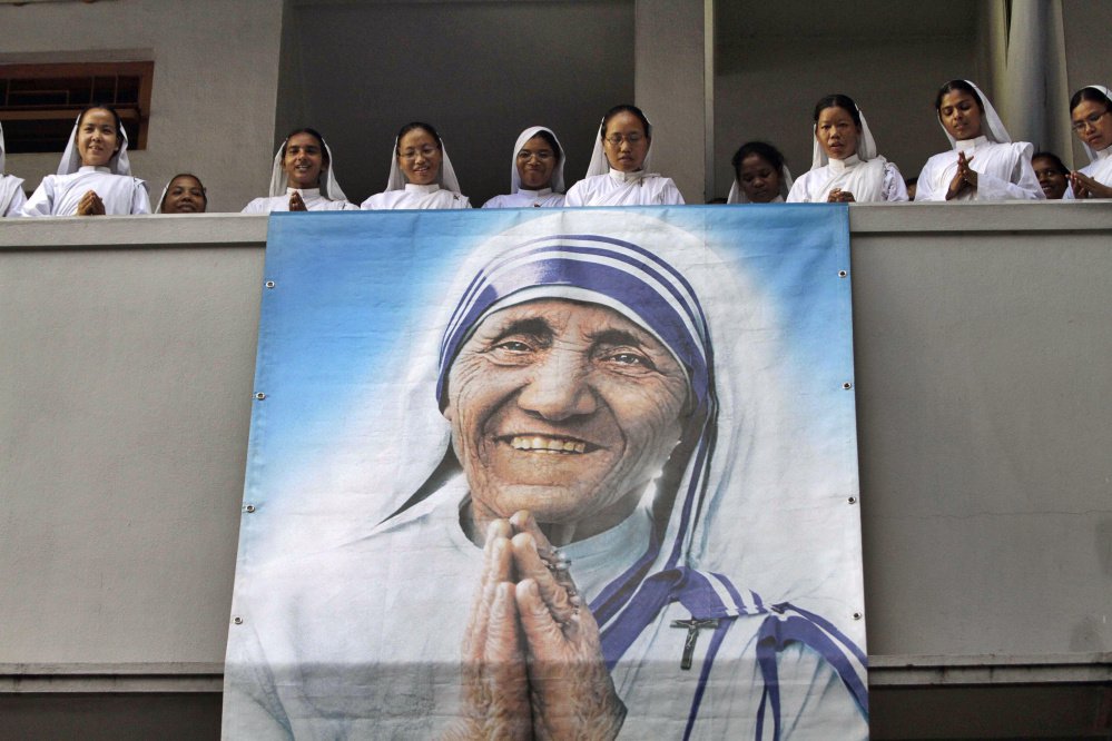 Nuns of Missionaries of Charity sing a hymn as a portrait of Mother Teresa hangs from a balcony during a congregation to mark her death anniversary in Kolkata India on Sept. 5 2011