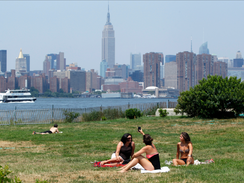 Women sun themselves during a hot summer day at a park in the Brooklyn borough of New