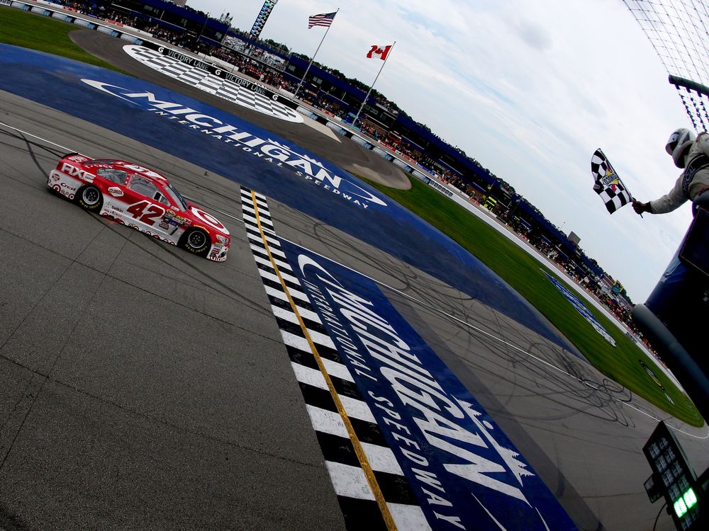 Kyle Larson driver of the #42 Target Chevrolet takes the checkered flag to win the NASCAR Sprint Cup Series Pure Michigan 400 at Michigan International Speedway on Aug. 28 2016 in Brooklyn Mich