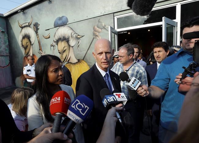 Florida Gov. Rick Scott center speaks with the news media after a news conference at Wynwood Walls Monday Sept. 19 2016 in the Wynwood neighborhood of Miami. The governor said the arts district is no longer considered a zone of active Zika transmiss