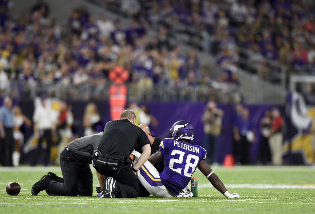 MINNEAPOLIS MN- SEPTEMBER 18 Adrian Peterson #28 of the Minnesota Vikings sits on the field as trainers tended to his knee in the third quarter of the game against the Green Bay Packers