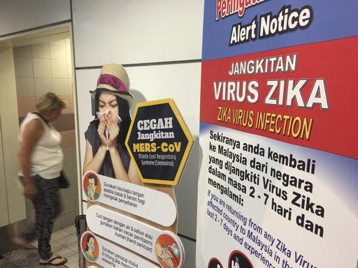 A traveller walks past a travel advisory on the Zika virus infection in Kuala Lumpur International Airport in Sepang Malaysia Sunday Aug. 28 2016. According to local reports Singapore Ministry of Health and National Environment Agency informed