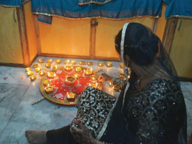 A woman lights clay lamps to celebrate Diwali