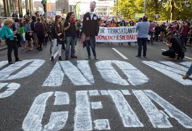 Sept. 20 2016 demonstrators walk over a spray painted sign on the street during a demonstration against international trade agreements in Brussels. The Belgian provide of Wallonia is proving how difficult it is for the Eu