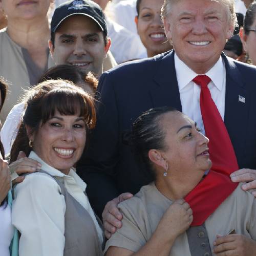 Republican presidential candidate Donald Trump grabs his tie as they pose for