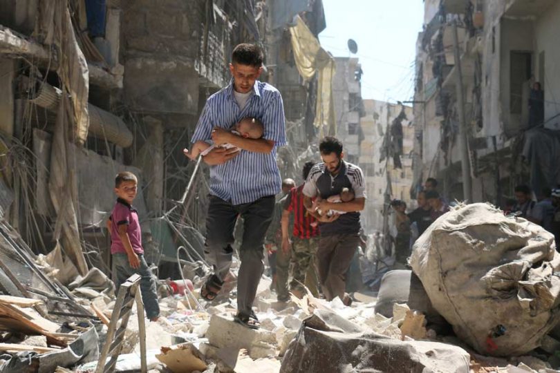 Syrian men carrying babies make their way through the rubble of destroyed buildings following a reported air strike on the rebel-held Salihin neighbourhood of the northern city of Aleppo