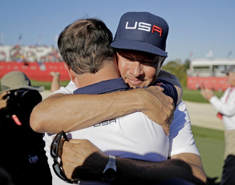 Captain Davis Love III right hugs Zach Johnson after the Americans wrapped up the Ryder Cup on Sunday