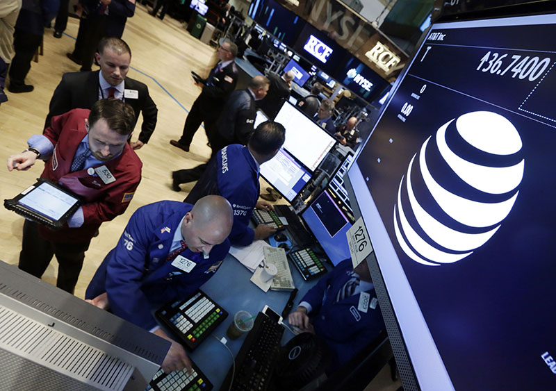 FILE- Traders gather at the post that handles AT&T on the floor of the New York Stock Exchange on Monday