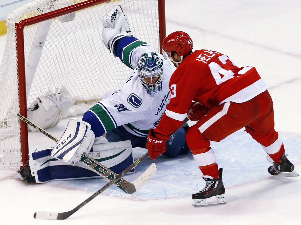 Vancouver Canucks goalie Ryan Miller stops a Detroit Red Wings center Darren Helm attempt in a shootout during an NHL hockey game Friday Dec. 18 2015 in Detroit. Vancouver won 4-3 in a shootout