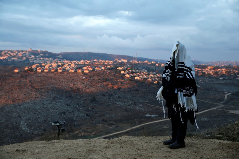 A Jewish man covered in a prayer shawl prays in the Jewish settler outpost of Amona in the West Bank