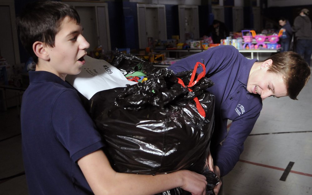 St. Michael School students Chris Bourdon left and Kyle Douin double bag gifts distributed Tuesday by the Salvation Army at the private Catholic school in Augusta