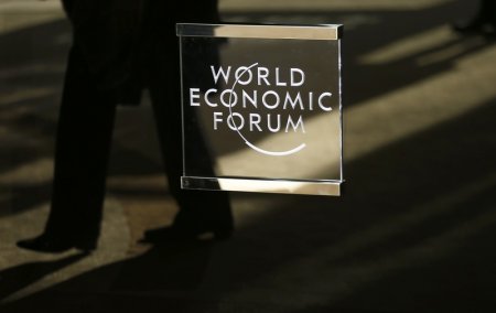 A man walks past the official logo of the World Economic Forum in Davos Switzerland