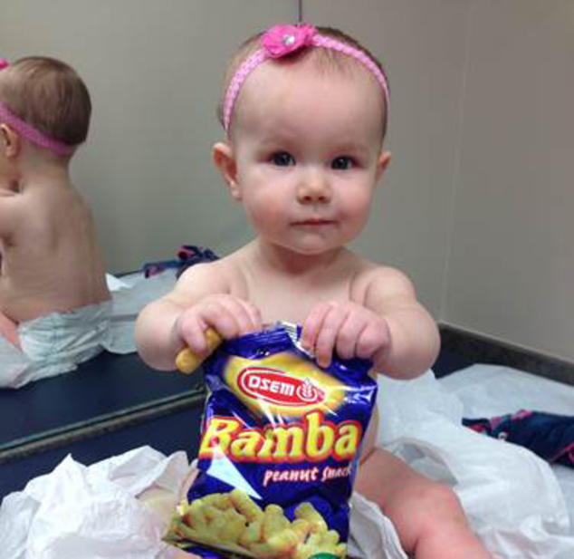 A nine-month-old girl holds a bag of peanut snacks in her pediatrician's office in Ohio