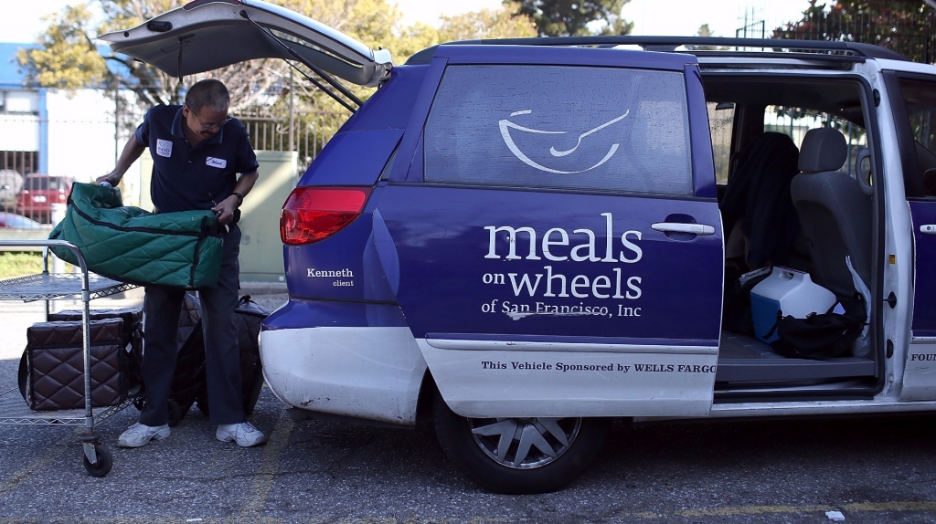 A Meals On Wheels of San Francisco driver loads meals into a van before making deliveries