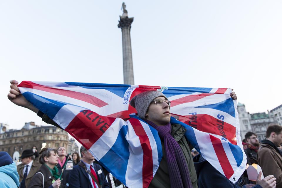 A man holds a Union Jack during a vigil at Trafalgar Square in London