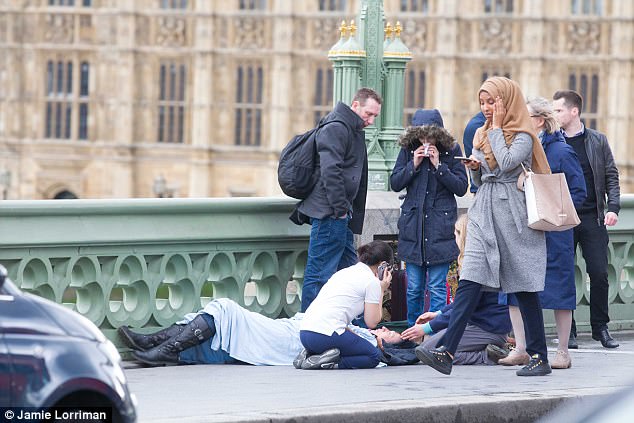 Trolled The pedestrian wearing a brown headscarf and grey coat was seen walking past a victim being treated on the pavement while looking at her mobile phone