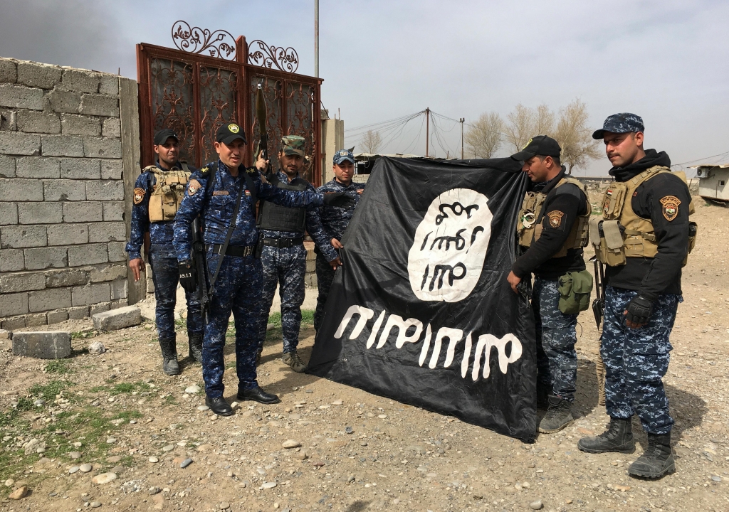 Iraqi troops hold up the flag of an Isis group they captured after regaining control of a neighbourhood in west MosulMOHAMMED SAAD  AP