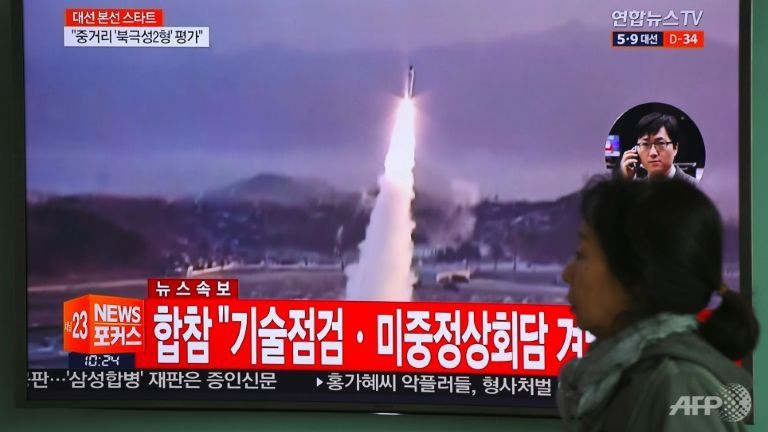 A woman walks past a television screen showing file footage of a North Korean missile launch at a railway station in Seoul. AFP  JUNG Yeon-Je