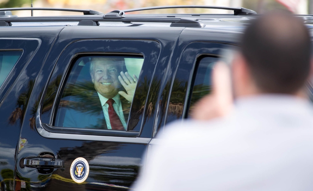 President Donald Trump waving from his limousine on the way to Palm Beach International Airport on Sunday