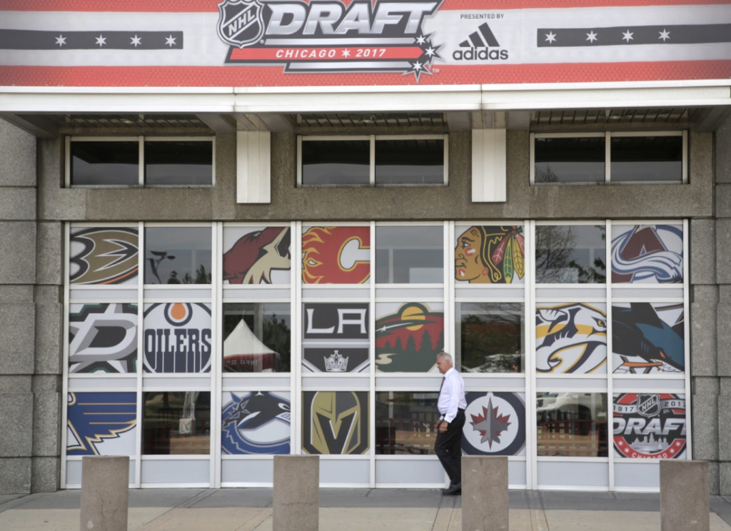 A man pass a United Center entrance with NHL team logos as preparation for the NHL Draft continue Thursday